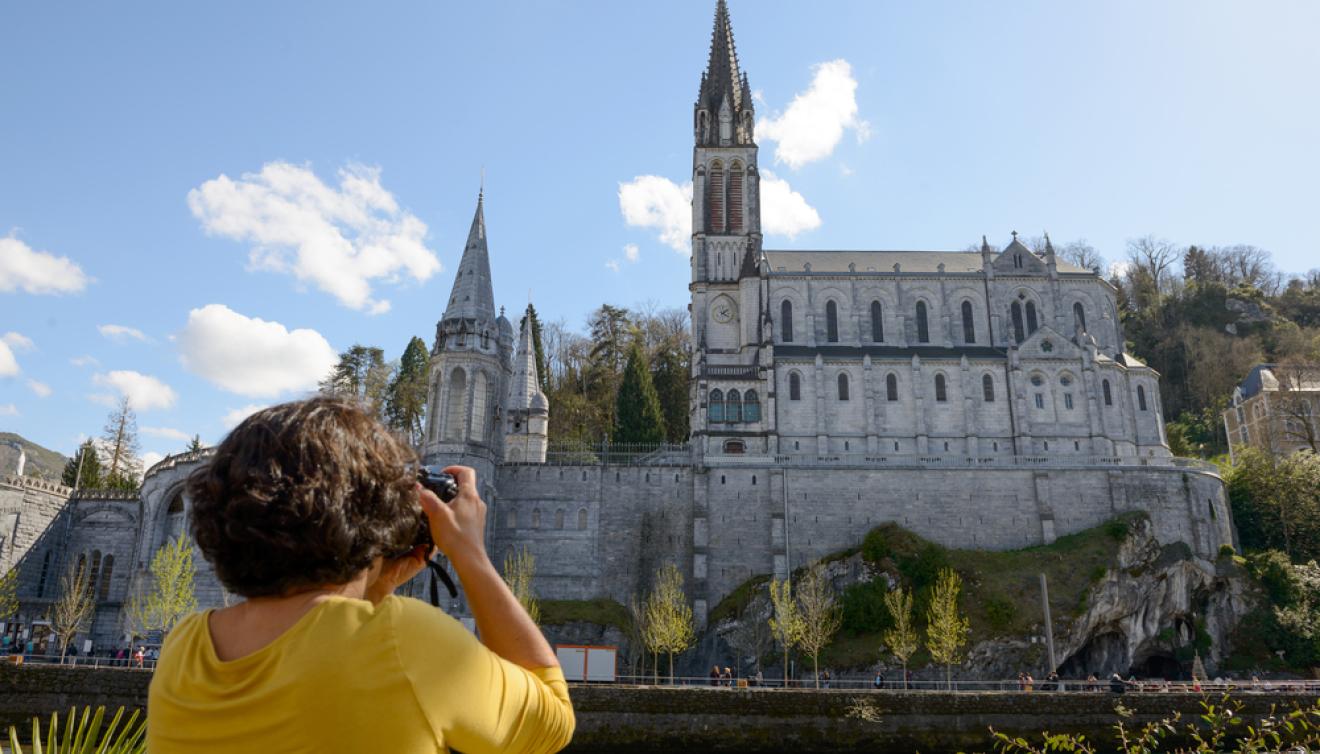 une femme prend une photo de la basilique de lourdes